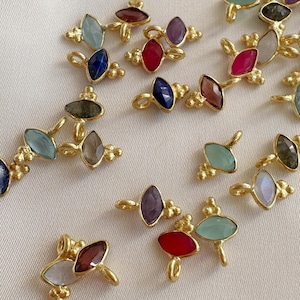 Peut inclure: Une collection de bijoux dorés, chacun orné de deux pierres précieuses ovales colorées. Les pierres précieuses sont de différentes couleurs, notamment le bleu, le rouge, le violet et le vert. Les bijoux ont un design délicat et orné.