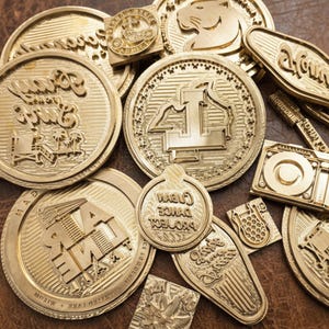 Puede incluir: Una colección de varios sellos de latón con diseños detallados. Los sellos presentan texto e imágenes, incluyendo un león, una motocicleta y las palabras "Clean Dance Project". Los sellos están dispuestos sobre una superficie de cuero marrón.