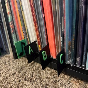May include: A close-up of a shelf with a collection of CDs. The CDs are organised by letter, with labels that say "A", "B", and "C".