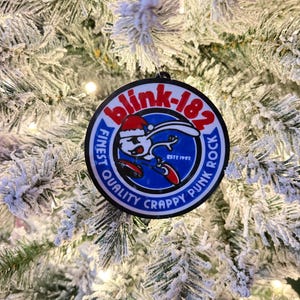 May include: A circular Christmas tree decoration with the Blink-182 logo, a cartoon bunny in a Santa hat, and the text "FINEST QUALITY CRAPPY PUNK ROCK". The ornament has a black border and hangs against a frosted Christmas tree.
