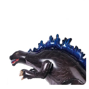 Op de afbeelding: Een zwarte opblaasbare dinosaurus met blauwe stekels op zijn rug. De dinosaurus staat in een brullende pose met zijn bek open.