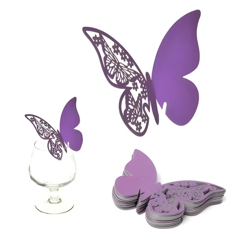 May include: Purple butterfly-shaped decorations. One butterfly is perched on a wine glass, while others are displayed separately. Some butterflies have intricate cut-out wing designs. The butterflies are made of a solid material and are a vibrant purple color.