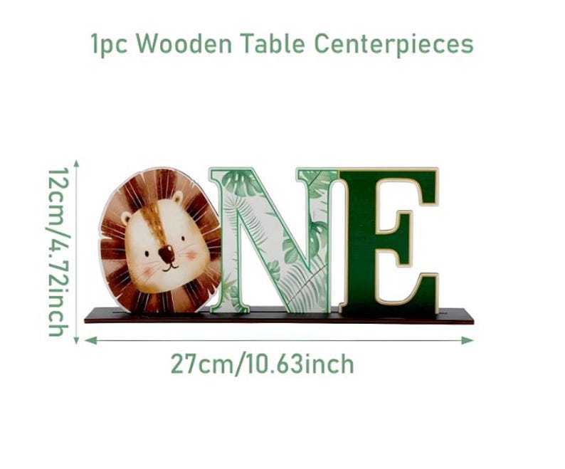 May include: A wooden table centerpiece spelling the word ONE, featuring a lion face for the letter O, a tropical leaf pattern on the letter N, and a solid dark green letter E. It measures 4.72 inches high and 10.63 inches wide.