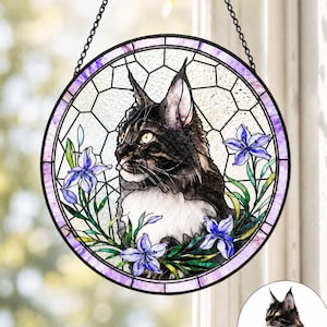 Peut inclure: Un attrape-soleil circulaire en vitrail représentant un chat noir et blanc aux yeux jaunes, entouré de fleurs d'iris violettes et de feuilles vertes. La pièce est encadrée par une bordure violette et inclut une chaîne métallique noire.