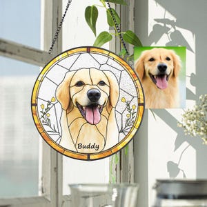 May include: A round, stained glass window featuring a smiling golden retriever dog with the name "Buddy" at the bottom. The window has a yellow border and is hanging from a chain. A smaller photo of the dog is to the right.