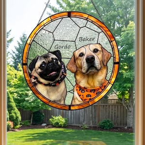 Peut inclure: Vitrail circulaire représentant deux chiens, un carlin nommé Gordo et un labrador nommé Baker, chacun portant un bandana. La fenêtre a une bordure orange et est suspendue devant une fenêtre avec vue sur un jardin.