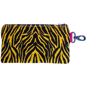 Könnte beinhalten: Eine kleine gelbe und schwarze Tasche mit Zebra-Muster, Reißverschluss und einem rosa und schwarzen Clip.