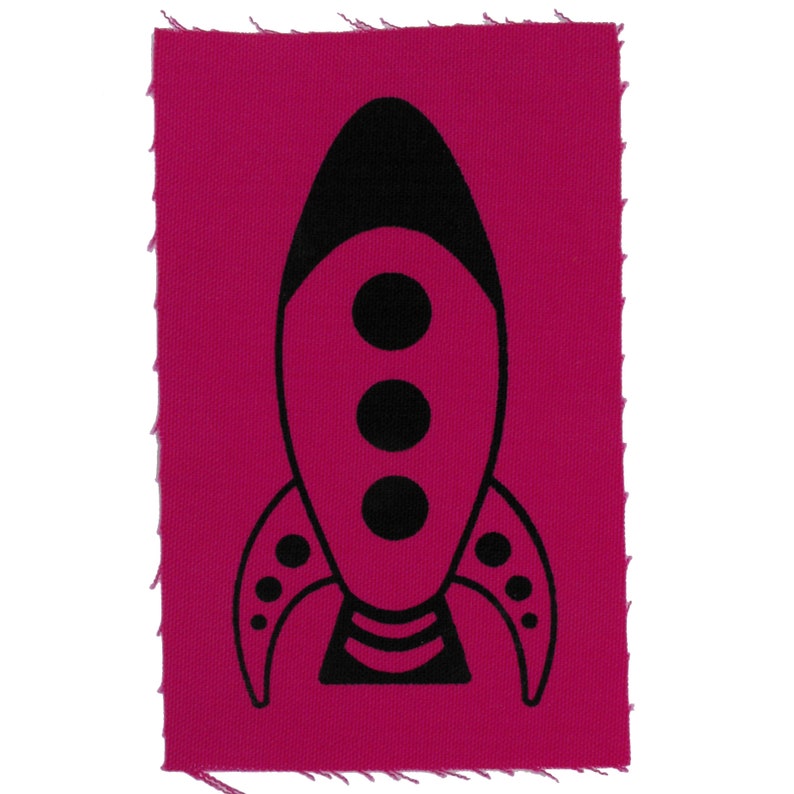 May include: A black rocket ship silhouette on a pink fabric patch. The rocket has three round windows and a striped tail.