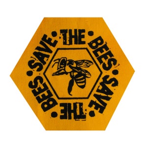 May include: Yellow hexagonal patch with the text "Save the Bees" repeated twice in a circle, with a black silhouette of a bee in the center.