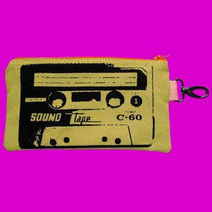 May include: A yellow canvas zippered pouch with a black and white graphic of a cassette tape. The tape reads "SOUND Tape C-60".