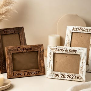 Può includere: Quattro cornici portafoto rettangolari in legno con testo inciso. Due cornici sono marrone scuro con le scritte 'Family' e 'Engaged Love Forever'. Due cornici sono bianco effetto invecchiato con 'MEMORIES' e 'Larry & Kelly 09.20.2023'.