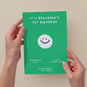 May include: A green birthday invitation with white text that reads "IT'S BENJAMIN'S 1ST BIRTHDAY." A white circle with a smiling face is in the center. Additional text includes the date, time, RSVP information, and address.