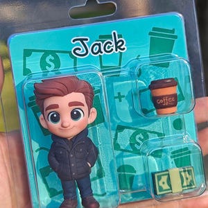 Op de afbeelding: Een verpakte beeldjesset met een stripfiguur genaamd Jack. De set bevat een Jack-figuur, een koffiekopje en een stapel geld. De achtergrond is turquoise met dollartekens en koffiekopjesafbeeldingen.