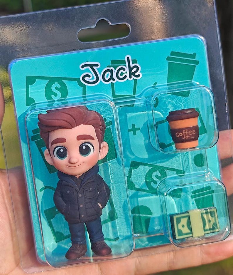 Op de afbeelding: Een verpakte beeldjesset met een stripfiguur genaamd Jack. De set bevat een Jack-figuur, een koffiekopje en een stapel geld. De achtergrond is turquoise met dollartekens en koffiekopjesafbeeldingen.