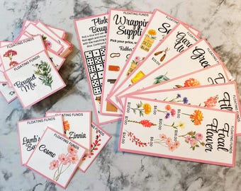 Puede incluir: Un conjunto de tarjetas blancas con bordes rosas, con ilustraciones florales y texto escrito a mano. Las tarjetas están etiquetadas con frases como "Floating Funds", "Bouquet Mix" y "Focal Flower". Algunas tarjetas muestran dados y precios.