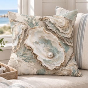 May include: A square throw cushion featuring a detailed print of multiple oyster shells in shades of beige, tan, and soft blue. A single, prominent, three-dimensional-looking white pearl is centred within the largest open oyster shell.