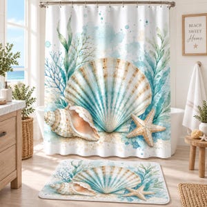 Puede incluir: Una cortina de ducha blanca y una alfombrilla de baño a juego con un estampado de acuarela de una gran concha en forma de abanico, una caracola en espiral y una estrella de mar, con algas y corales en tono azul verdoso sobre fondo azul y blanco.