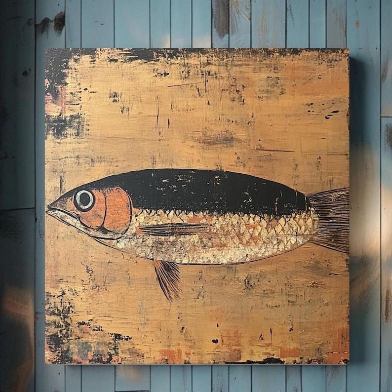 May include: A square wall art piece featuring a stylized fish illustration centered on a textured, metallic gold background. The fish has a black upper body, a copper-toned head, and a gold-leaf style scale pattern, with dark distressed edges.
