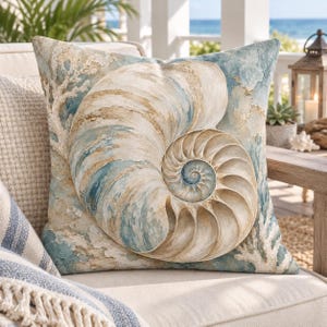 Op de afbeelding: Een vierkant sierkussen met een grote, gedetailleerde nautilusschelp-afbeelding in tinten beige, crème en gedempt blauw. Het ontwerp bevat textuurrijke, koraalachtige patronen op de achtergrond, wat een kustesthetiek op de stof creëert.