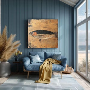 May include: A large, rectangular painting of a fish with a black back and orange eye hangs on a blue wall. The fish is painted on a gold-toned background. A blue sofa with pillows and a yellow blanket are in front of the wall.