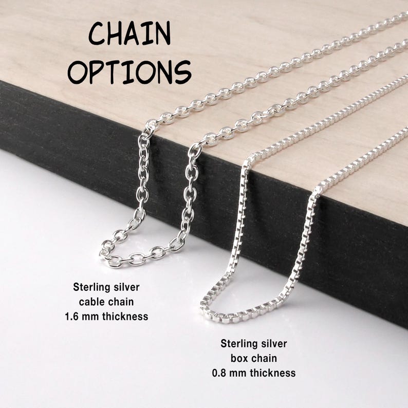 May include: Two silver necklaces labeled CHAIN OPTIONS. One is a sterling silver cable chain with a 1.6 mm thickness, and the other is a sterling silver box chain with a 0.8 mm thickness. Both chains are metallic silver and feature distinct link styles.