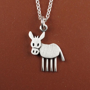 May include: A silver donkey pendant on a necklace. The pendant is a stylized design of a donkey with a textured body, visible ears, and four vertical lines for legs. The chain is also silver.