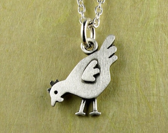 May include: A silver-toned metal pendant shaped like a chicken, featuring a brushed finish and a small circular eye detail. The pendant hangs from a delicate silver-toned chain link necklace, showcasing a simple, flat, and stylized bird design.