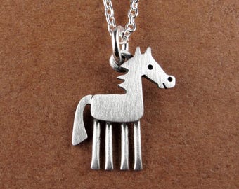 May include: A silver-toned metal necklace featuring a stylized horse pendant with a brushed finish. The pendant is suspended from a delicate silver-toned chain link necklace, showcasing a simple, flat, and geometric design of a horse silhouette.