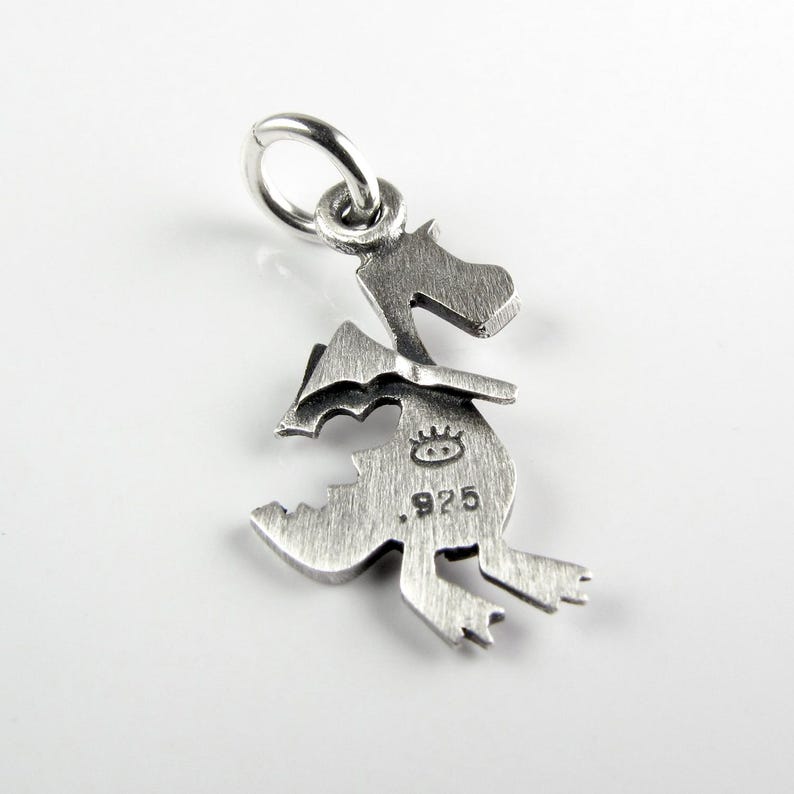 May include: A silver-colored metal charm shaped like a dragon hatching from an egg. The charm features a brushed finish, a small jump ring at the top, and is stamped with a small eye-like symbol and the number 925 on the front surface.
