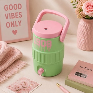 May include: A light green beverage cooler with a pink lid and handle. The cooler features the number 1908 in pink text with a dripping effect on the upper section. It includes a small pink spigot at the base for dispensing liquid and a circular opening on the lid.