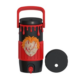 May include: A black and red cylindrical beverage container featuring a molded 3D face of a character with orange hair and facial scars. The top section has a red handle and red dripping paint details. A separate black circular lid is placed to the right.