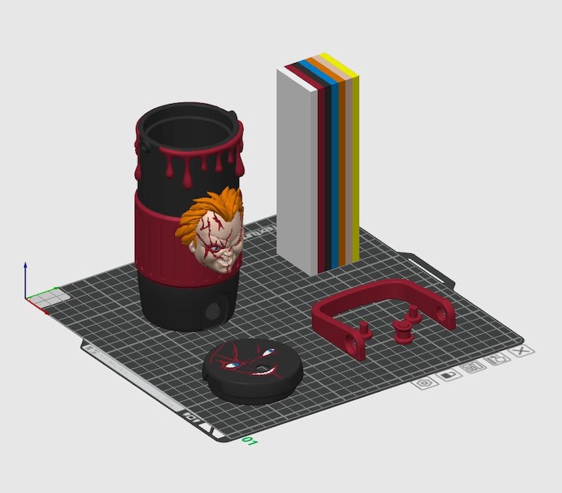 May include: A black cylindrical tumbler with red drip accents and a 3D relief of a scarred character face. Includes a matching black lid with a graphic of a face, a red U-shaped handle component, and a vertical stack of colored rectangular blocks.