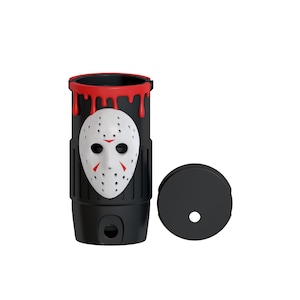 May include: A black cylindrical tumbler featuring a white hockey mask with red accents on the front. The top rim has a red dripping paint effect. A separate black circular lid with a central hole is positioned to the right of the tumbler.