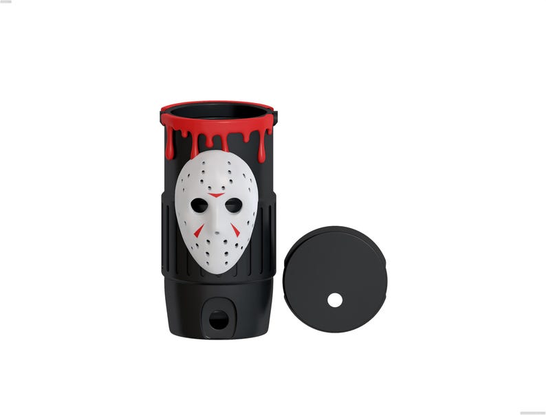 May include: A black cylindrical tumbler featuring a white hockey mask with red accents on the front. The top rim has a red dripping paint effect. A separate black circular lid with a central hole is positioned to the right of the tumbler.