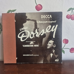 May include: Vintage vinyl record album cover featuring Jimmy Dorsey and his orchestra. The album, titled 'Contrasting Music,' is from the Decca album No. 185 popular series. The cover is predominantly black and white with a sepia-toned spine.