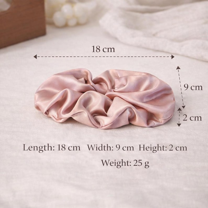 K&ouml;nnte beinhalten: Ein hellrosa Satin-Haargummi, 18 cm lang, 9 cm breit und 2 cm hoch. Das Haargummi ist ein weiches, gerafftes Stoffaccessoire, ideal zum Zusammenbinden der Haare. Gewicht: 25 g.