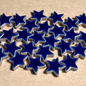 Könnte beinhalten: Ein Haufen blauer, sternförmiger Fliesen aus Keramik. Die Fliesen haben einen silbernen Rand und eine glänzende Oberfläche.
