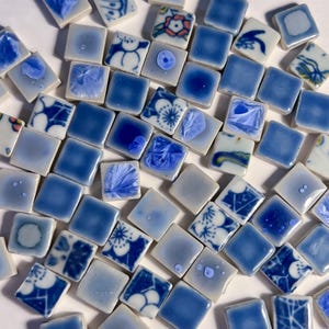 Può includere: Una collezione di tessere per mosaico in ceramica quadrate in varie tonalità di blu e bianco. Le tessere presentano un mix di colori solidi, smalti cristallini e intricati motivi floreali o astratti, con una finitura lucida e uniforme.