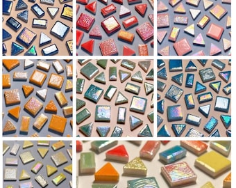 Può includere: Una collezione di piastrelle a mosaico colorate in varie forme, tra cui quadrati, rettangoli e triangoli. Le piastrelle presentano finiture iridescenti nelle tonalità di blu, arancione, rosa, verde e giallo. Le piastrelle sono disposte su uno sfondo neutro.
