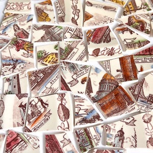 Könnte beinhalten: Eine Ansammlung zerbrochener Keramikteile mit verschiedenen Illustrationen und Textfragmenten. Die Fragmente zeigen Bilder von Gebäuden, Wahrzeichen und Texten wie "Sandy Hook", "Atlantic City" und "Trenton". Die Farbpalette umfasst Beige, Braun und Rot.