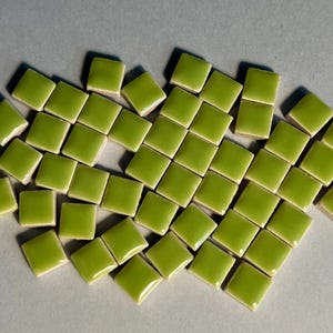 Peut inclure: Un tas de petites tuiles carrées en céramique verte. Les tuiles sont brillantes et de couleur vert clair.