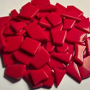 Peut inclure: Un tas de carreaux de mosaïque rouges brillants de différentes formes géométriques. Les carreaux sont d'un rouge vif et uni et semblent être en verre ou dans un matériau similaire. Les formes comprennent des rectangles, des triangles et des trapèzes, pour les projets de bricolage.