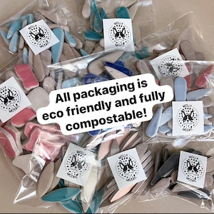 May include: Assortment of ceramic mosaic tiles in various shapes and colors, packaged in clear plastic bags. The bags are labeled with a logo that says "Molly Mosaic". The text "All packaging is eco friendly and fully compostable!" is written on a white sticker.