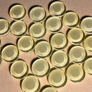 Peut inclure: Une collection de 20 carreaux de verre ronds, translucides, de couleur jaune pâle. Les carreaux sont disposés en quinconce.