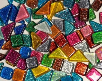 Puede incluir: Surtido de pequeñas baldosas de vidrio brillantes en varias formas y colores, incluyendo cuadrados, triángulos y rectángulos. Las baldosas son perfectas para proyectos de artesanía y mosaico.
