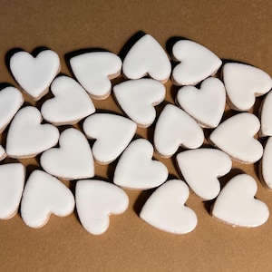 May include: A collection of white ceramic heart-shaped tiles. The tiles are arranged in a random pattern and are all the same size.