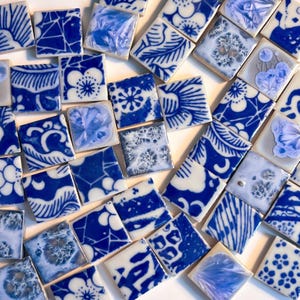 Peut inclure: Une collection de carreaux de céramique carrés présentant une variété de motifs bleus et blancs, incluant des motifs floraux, des formes géométriques et des textures cristallines, disposés en vrac avec des finitions brillantes visibles.