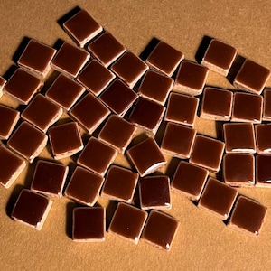 Pode incluir: Um monte de azulejos quadrados de cerâmica marrom. Os azulejos são brilhantes e têm um leve brilho.