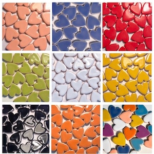 Könnte beinhalten: Neun Quadrate mit herzförmigen Fliesen in verschiedenen Farben. Die Farben umfassen Pfirsich, Blau, Rot, Grün, Weiß, Gelb, Schwarz, Orange und eine Mischung aus Blau, Lila, Orange und Gelb. Die Fliesen haben eine glänzende Oberfläche.
