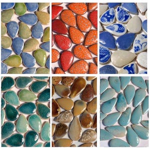 Puede incluir: Una colección de azulejos de cerámica en forma de lágrima dispuestos en seis grupos de colores distintos. Los azulejos presentan varios acabados, incluyendo patrones sólidos, moteados, agrietados y florales en azul y blanco en tonos verdes, azules, naranjas, marrones y crema.